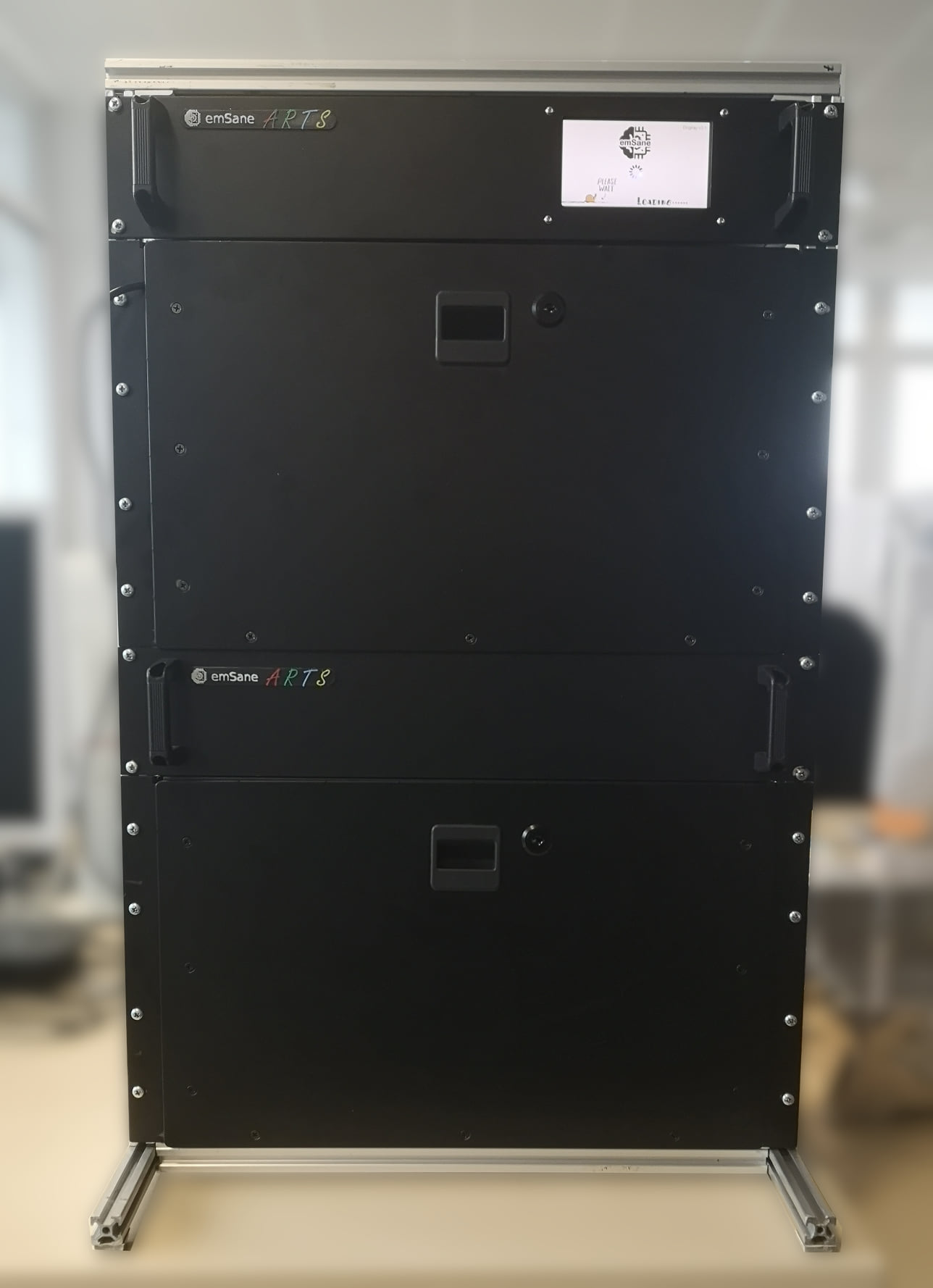 Front view of two stacked emSane ARTS Box units in a 19-inch rack, showing the status display and access panels.