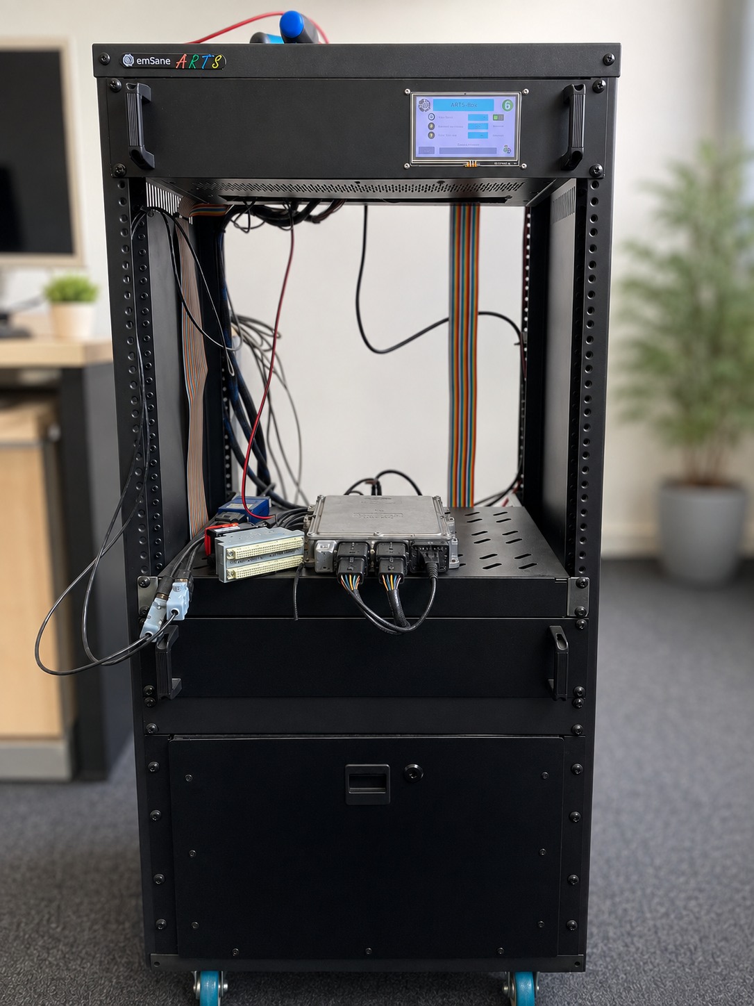 Front view of an emSane ARTS Box test rack with an automotive ECU and connected test hardware.